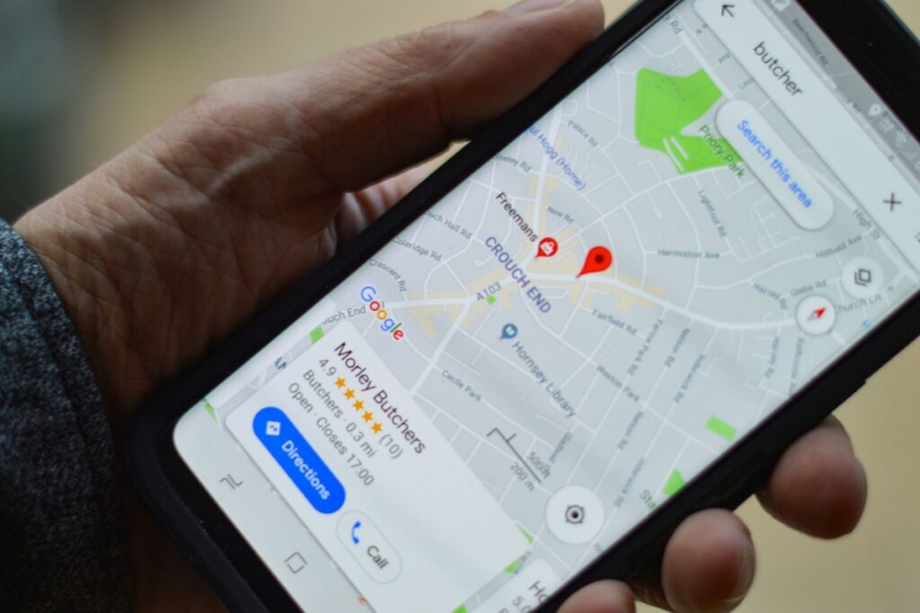 Osoba szuka lokalnej firmy na Mapach Google w smartfonie, przykład lokalnego SEO i pozyskiwania klientów z okolicy