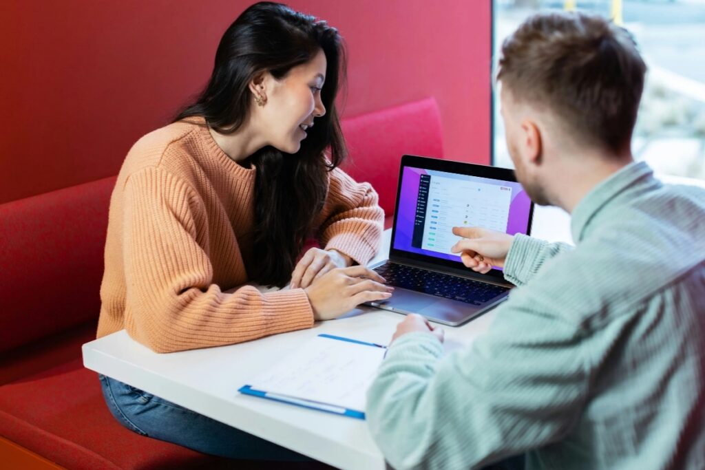 Dwie osoby omawiają opiekę nad stroną internetową przy laptopie, analizując ustawienia i działanie witryny