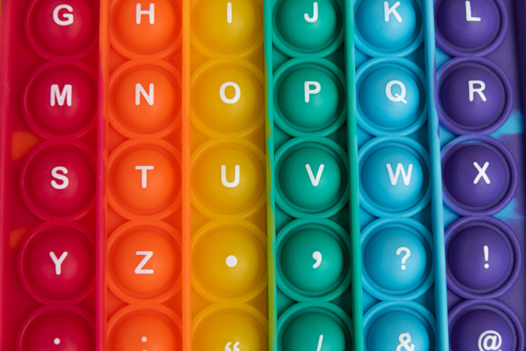 Różne litery alfabetu w odmiennych fontach na tle kolorowej palety – dobór czcionek i kolorów na stronę internetową