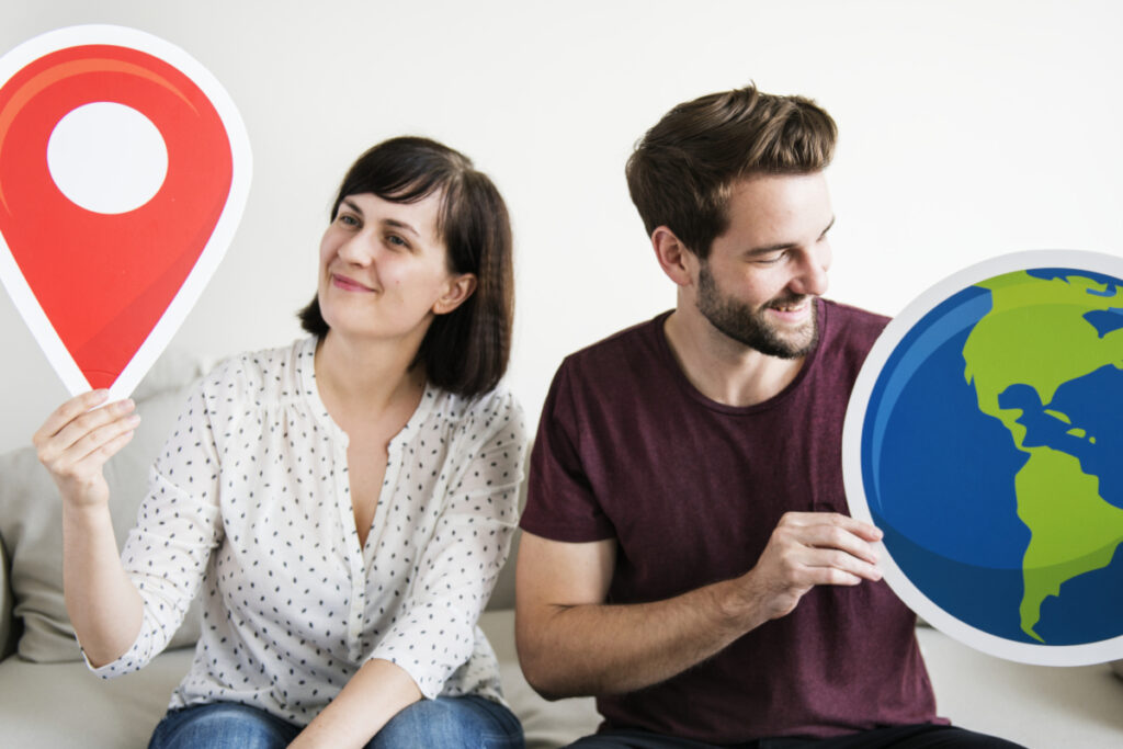 Dwie osoby trzymają symbole lokalizacji i globusa – wybór między SEO lokalnym a ogólnokrajowym dla firmy